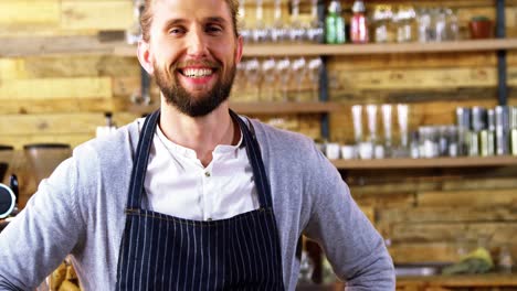 smiling waiter standing with hands on hip at counter