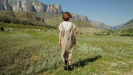 woman walking in a scenic mountain pasture with cows