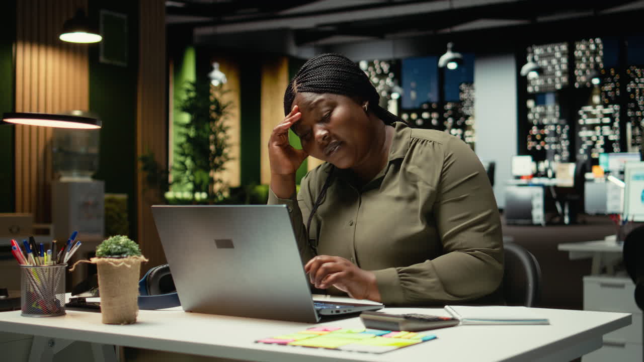 African american woman realizing she works alone late at night in the office