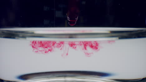 process of dropping blood from pipette into water. blood drops flowing in water