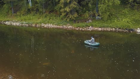 hombre pescando desde un bote inflable en un río del bosque