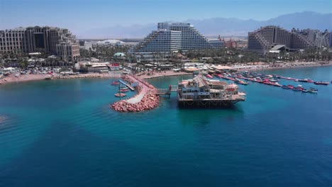 aerial view of eilat, israel, a bustling coastal resort city with hotels, a pier, and numerous boats on the red sea