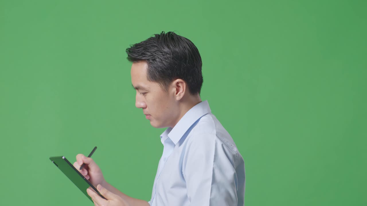 스튜디오에서 녹색 화면 배경에서 는 동안 태블릿에서 메모를 말하는 아시아 사업가의 측면 뷰 클로즈업