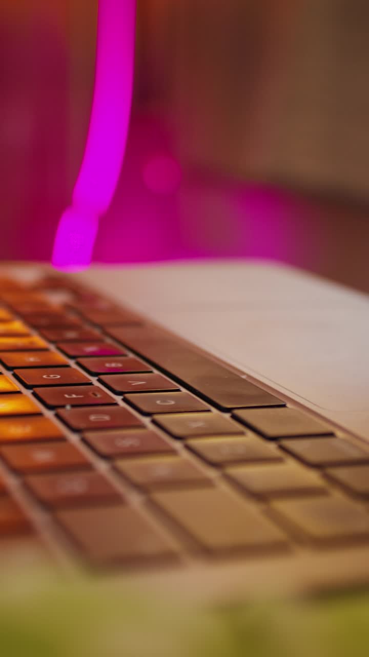 Close-up of a laptop keyboard with pink light