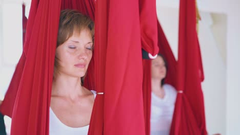 una señora bonita se sienta en una hamaca roja y practica la meditación