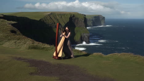 woman playing harp on a scenic cliff by the ocean