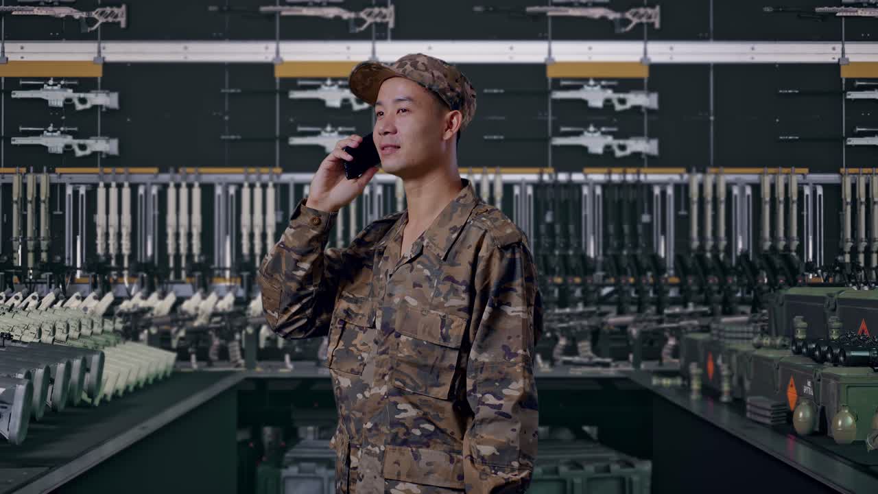 Vista laterale di un soldato asiatico che parla al telefono e si guarda intorno in un arsenale militare
