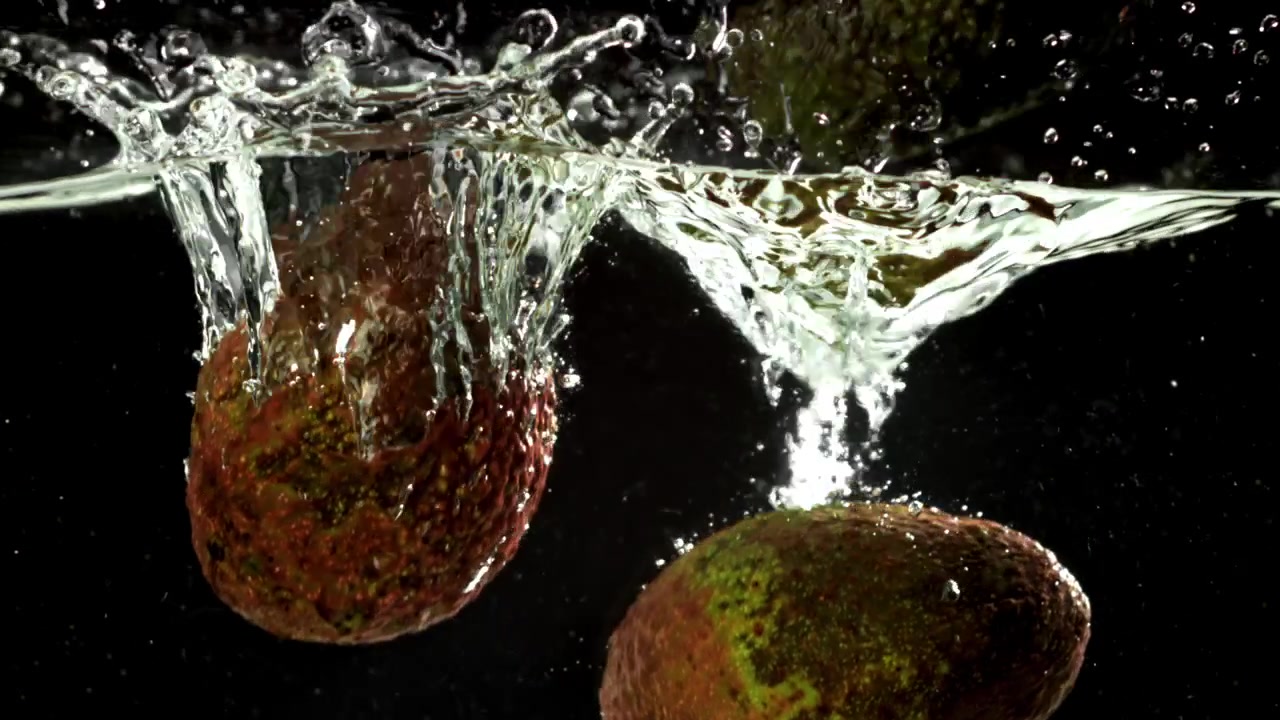Avocado che cadono nell'acqua con schizzi in slow motion