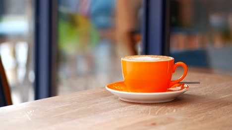 a cup of coffee with latte art on a wooden table in a cafe