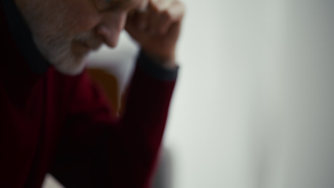 Uomo anziano pensieroso che tiene un bicchiere vuoto