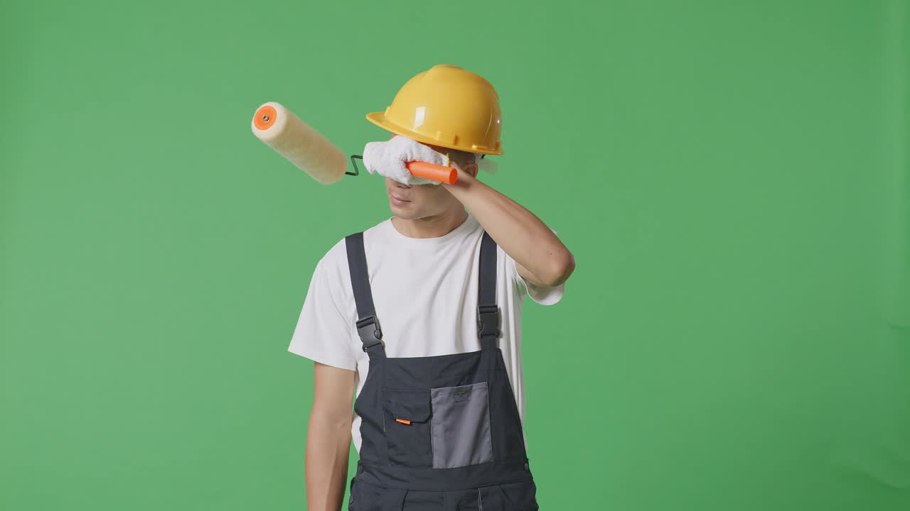 Asian Man Painter Wearing Safety Helmet Wiping The Sweat And Being Tired While Standing In The Green Screen Background Studio