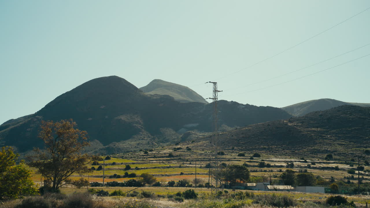 Paesaggio montano suggestivo con dolci colline e linee elettriche che attraversano la campagna mediterranea. Scenario naturale combinato con infrastrutture discrete, ideale per viaggi, ambiente ed energia.