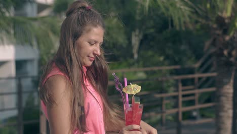 summer wind blows through long hair and girl tastes cocktail