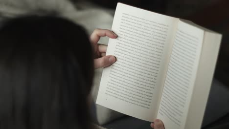 Close-up-shot-of-Reading-time-of-female-with-a-book-on-sofa-at-living-room