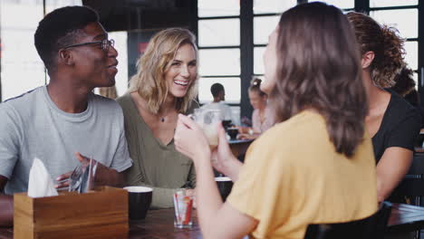 Eine-Gruppe-Von-Freunden-Sitzt-Am-Tisch-In-Einem-Belebten-Café-Und-Unterhält-Sich