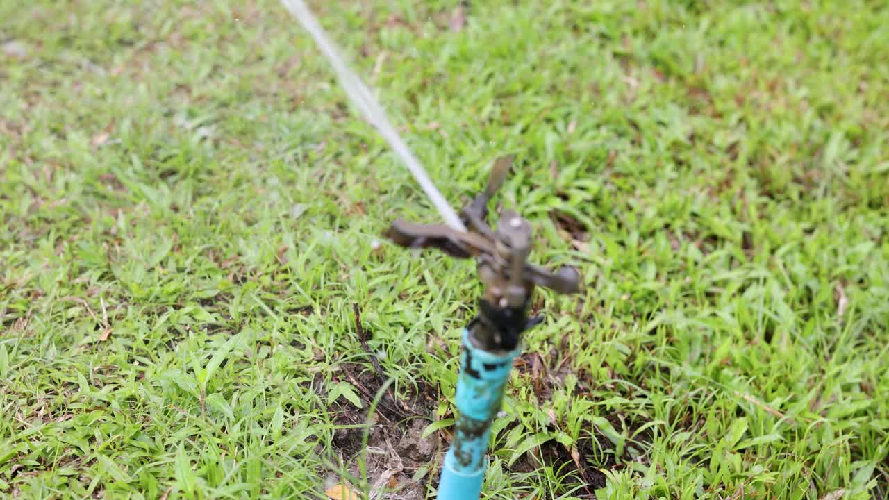 Primo piano di un irrigatore a impatto automatico che spruzza acqua su un prato verde e rigoglioso