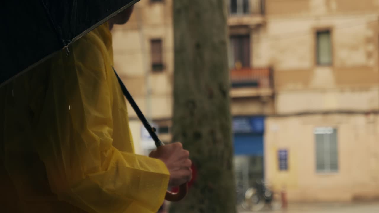 Business man tourist person with umbrella and raincoat on rainy european city street, lights reflecting, walking in Barcelona or Amsterdam during the rain