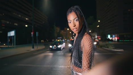 trendy brunette girl crossing night traffic road closeup. woman posing street