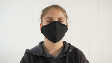 Close-up-of-causasian-teen-in-black-hoodie-wearing-a-large-black-anti-virus-face-mask