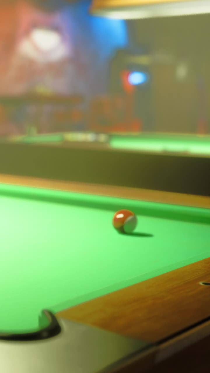 Pool table in a dimly lit room with a red ball on the green felt