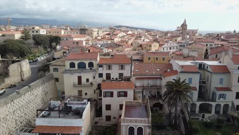 Toma-Aérea-Sobre-El-Casco-Antiguo-De-Alghero,-Cerdeña,-Con-Vistas-Al-Paisaje-Urbano-En-Un-Hermoso-Día-Claro