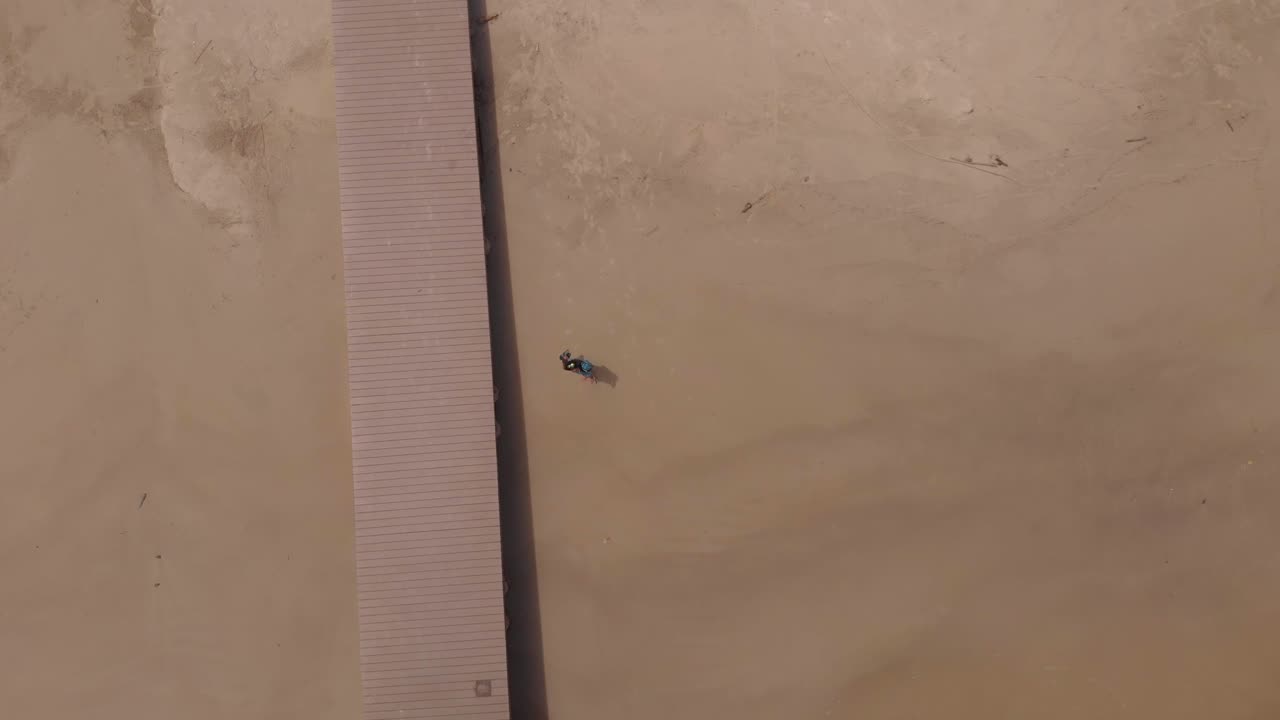 Ripresa aerea di una donna che cammina verso un molo e una cabana su una spiaggia caraibica