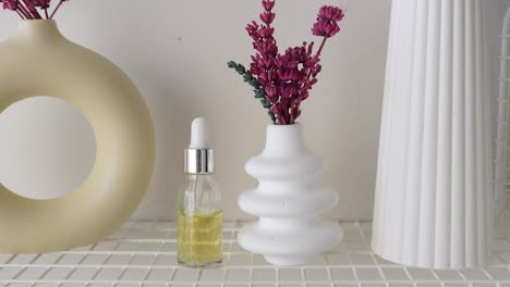 dried pink flowers, decorated shelf with vase and essential oil