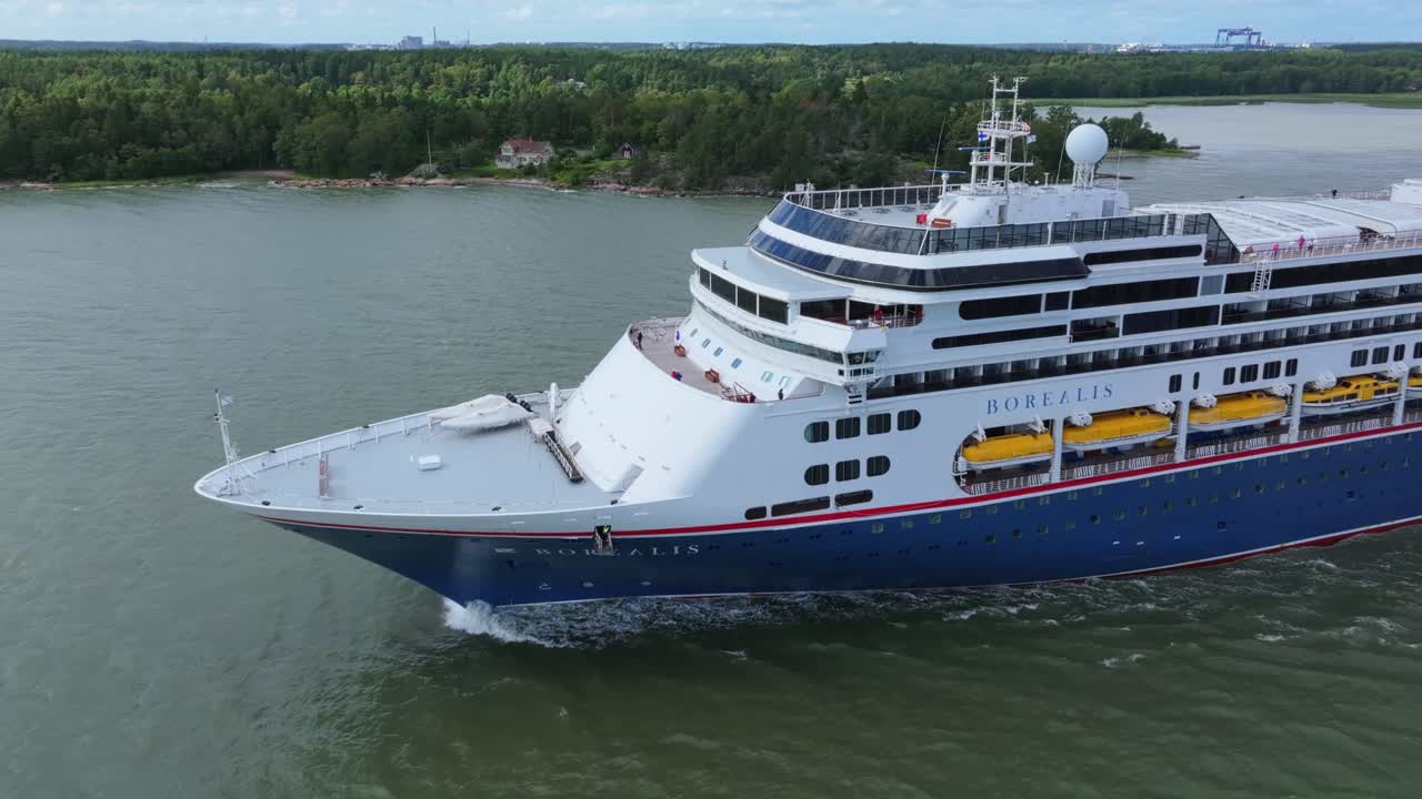 Fred.Olsen Cruise Lines passenger ship BOREALIS making way ahead in Finnish archipelago on departure. Low altitude aerial side view of bow.