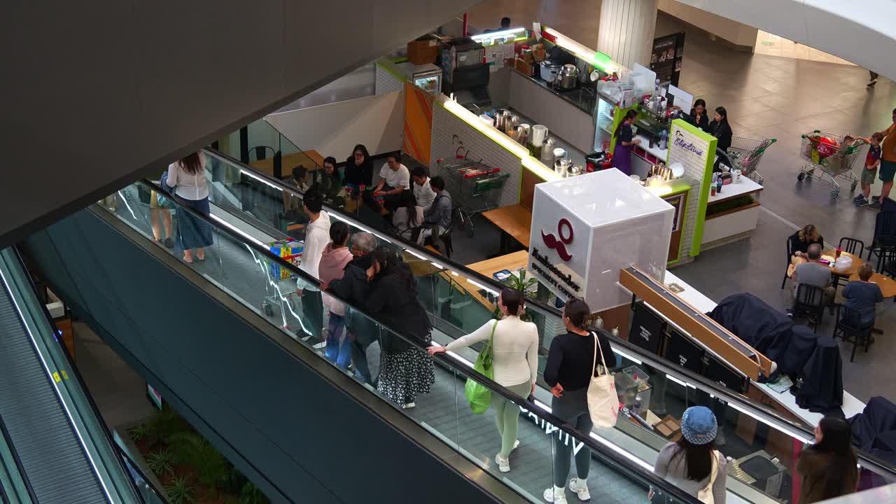 Toowong village shopping centre in Brisbane inner city suburb, patrons taking the escalators down, slow motion shot.