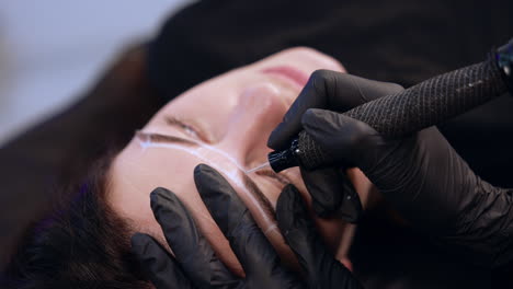 permanent make up instrument held in the gloved hand of a brow master. cosmetology and beauty concept.