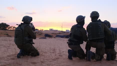 Slow-motion-of-a-team-of-combat-soldiers-planning-its-raid-on-a-sandy-desert-area-at-sunset