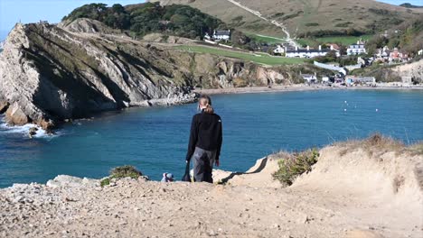 英國南部的盧爾沃斯洞穴 (lulworth cave) 的海灘上,一個女孩在海邊散步,