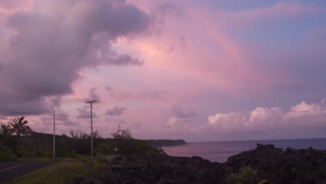 Pacific-island-coastline-at-sunset-with-pink-and-purple-clouds-and-black-rock-cliffs