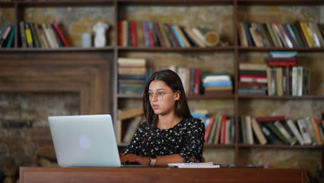 mujer joven trabajando en una computadora portátil en una biblioteca