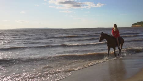 mujer a caballo en la playa al atardecer