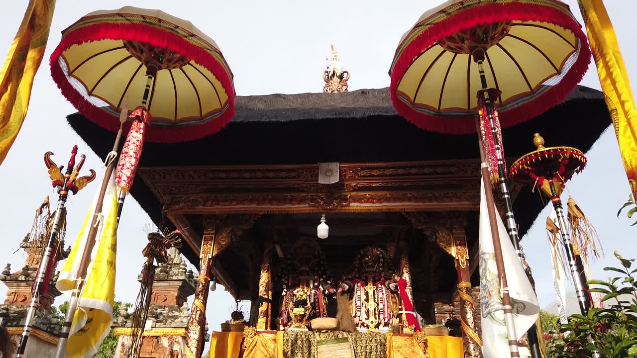 altar con paraguas en el antiguo templo balinés con ofrendas y objetos religiosos sobre un cielo azul claro, ceremonia en el antiguo bali, indonesia