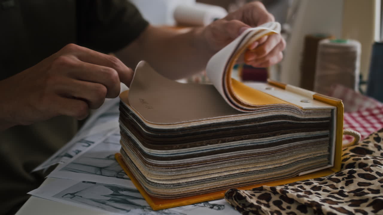 Hænder på atelierspecialist, der vælger stof