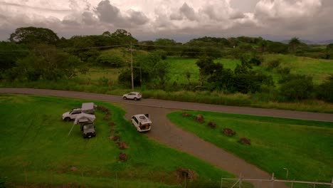 Cinematic-drone-clip-of-camper-4x4-with-tends-camping-outside-in-a-green-pasture-in-nature