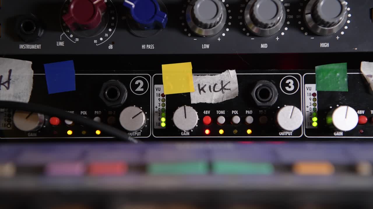 ajustar las pernas de ganancia en un preamplificador de micrófono analógico de época durante una sesión de grabación