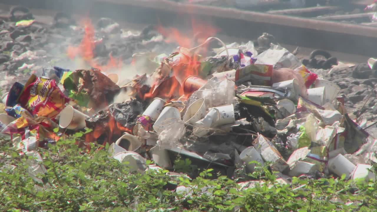 Burning rubbish piles close by railroad tracks
