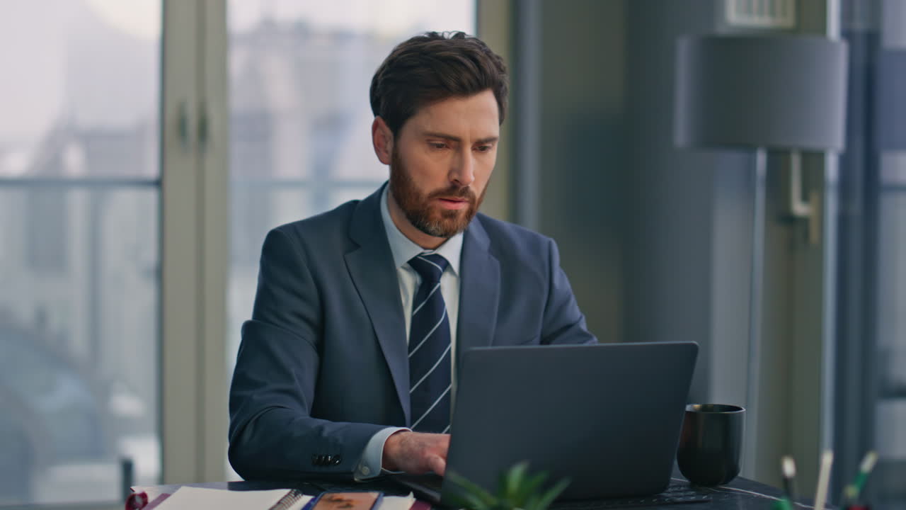 uno specialista serio che lavora su un portatile seduto in ufficio in primo piano. un uomo che scrive su un computer.