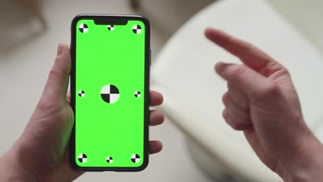 dedo apuntando en el teléfono inteligente con pantalla verde con marcadores de seguimiento luego pulgares hacia arriba, orientación de retrato