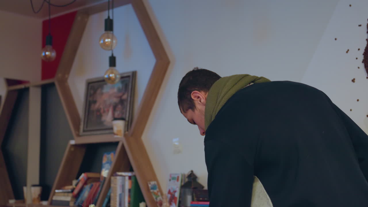 Pemuda membaca dengan cahaya. Individu muda sangat asyik membaca dalam lingkungan pencahayaan hangat. Remaja tenggelam dalam literatur sambil diterangi cahaya sekitar yang lembut di suasana nyaman.