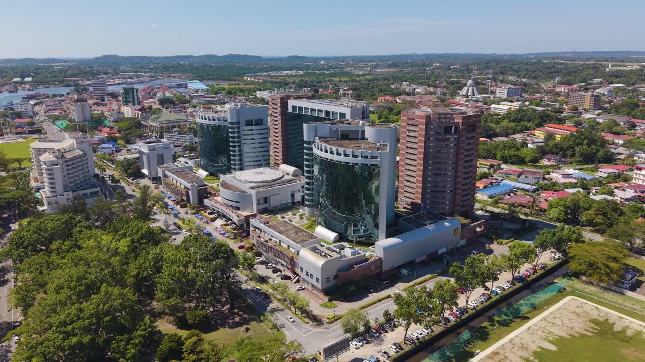 Push in aerial shot of the Labuan Financial Park in Victoria, Malaysia. The shot showcases the modern high-rise office towers, surrounding development, and roads