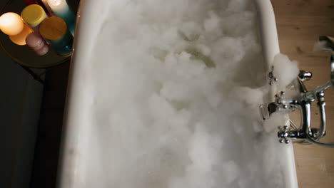 luxury bathtub foamy water at candles room top view. bubbles filled bath evening