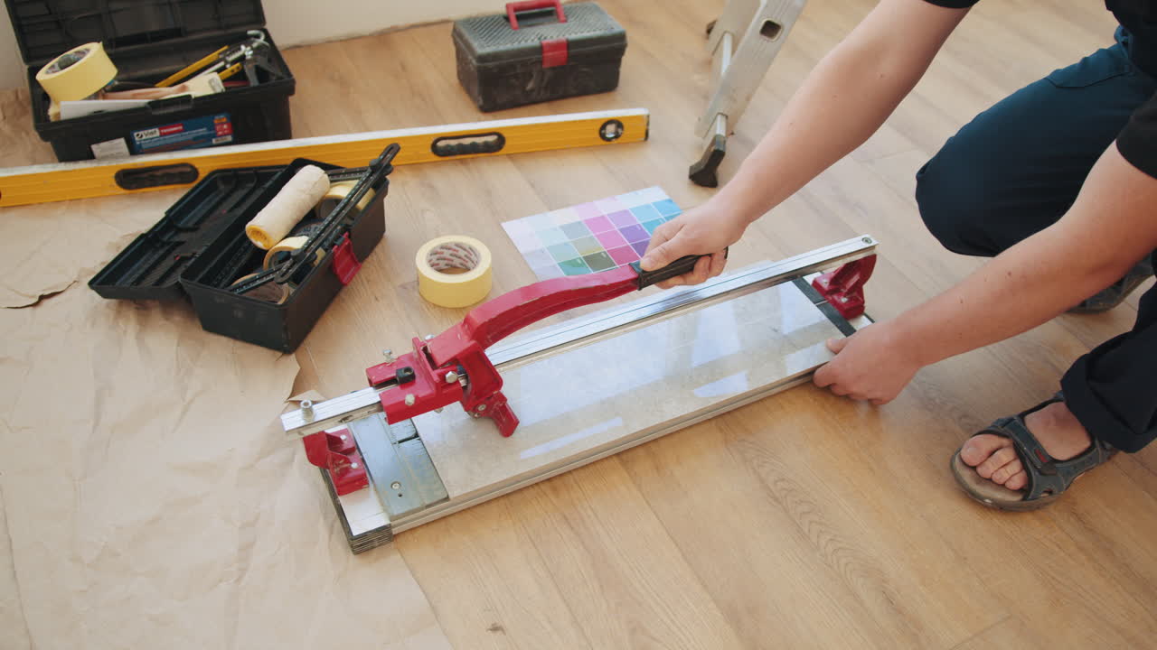 persona cortando azulejos en un piso de madera.