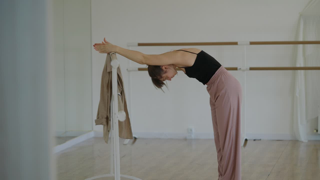 Woman Stretching at Barre in Dance Studio