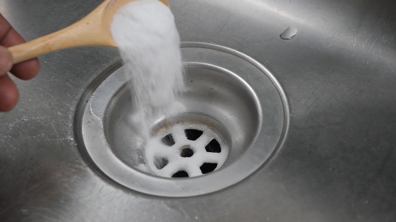 Pouring Baking Soda into a Kitchen Sink Drain
