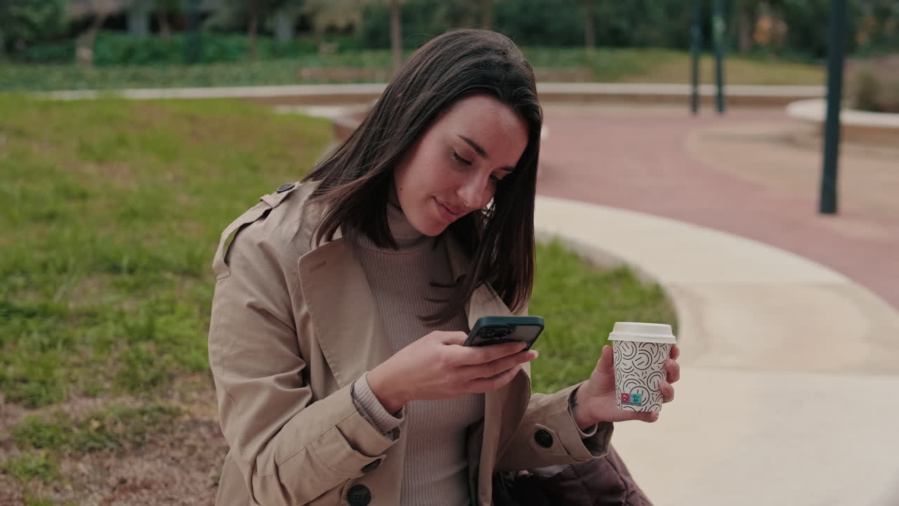 Mujer con teléfono y café en el parque