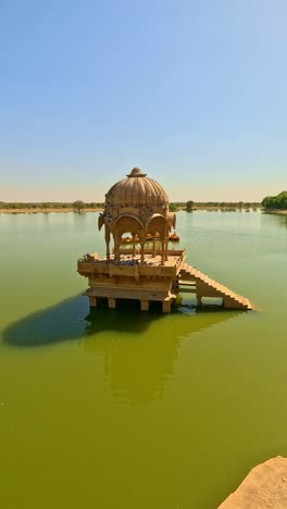 gadsisar lake in jaisalmer sparkles under the golden rajasthan sun, mirroring ancient elegant pavilions in calm water offering a serene escape in the heart of the desert's timeless beauty india